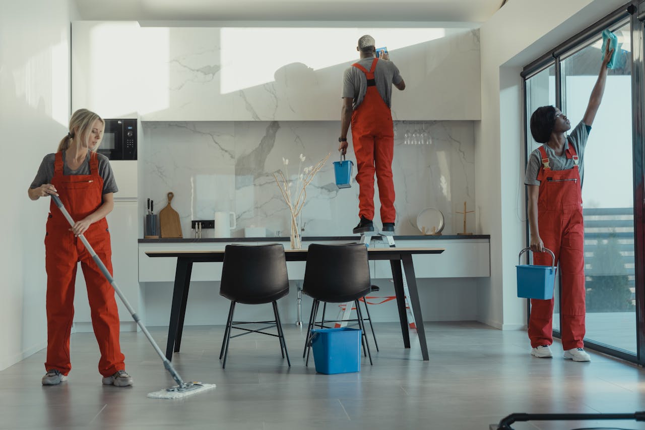 services-03 Group of cleaners in red uniforms mopping and wiping glass in a modern dining room.